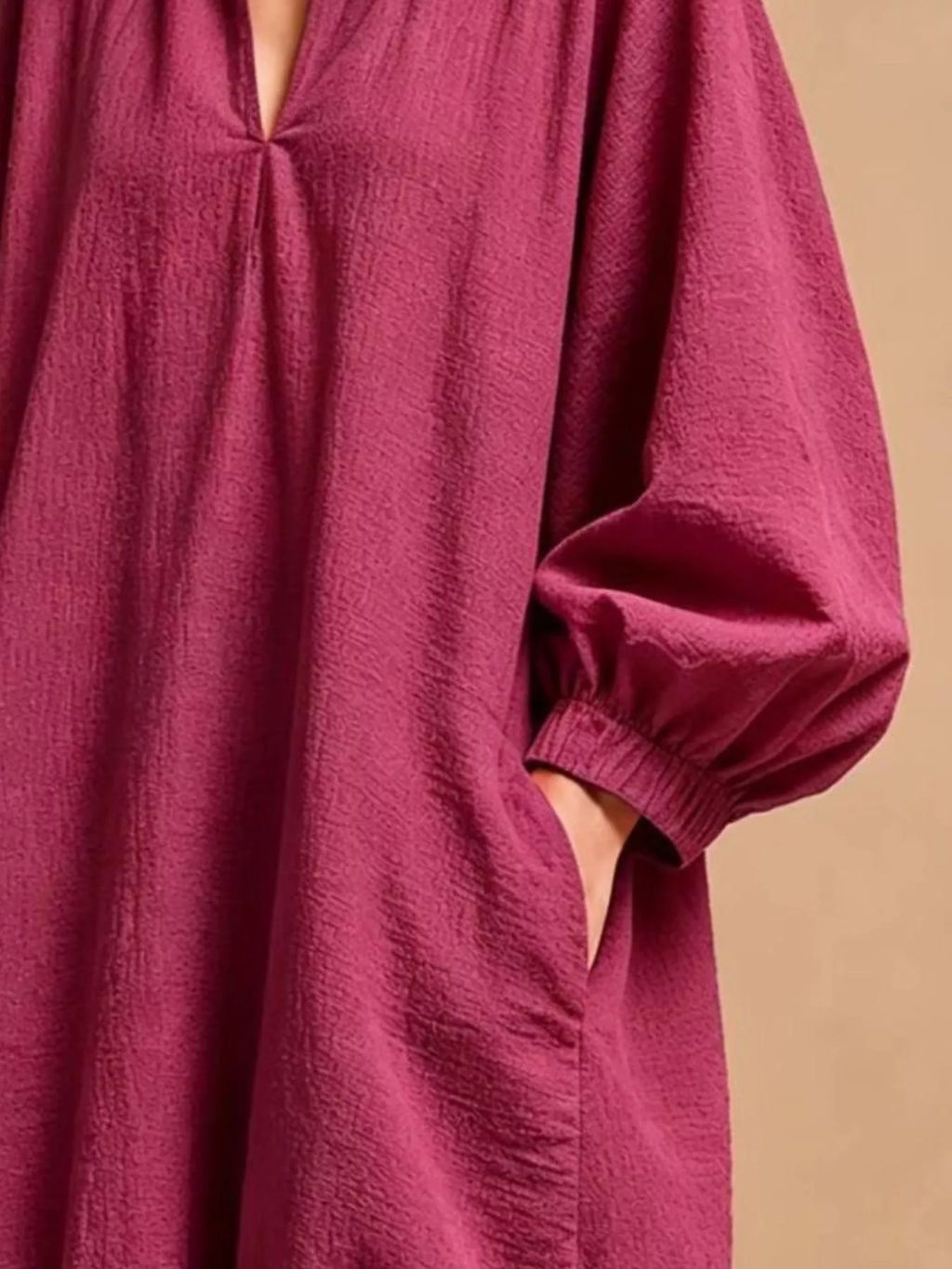 Macro de la manche et de la zone de poche de la robe magenta soulignant le poignet froncé et la profondeur de la poche latérale