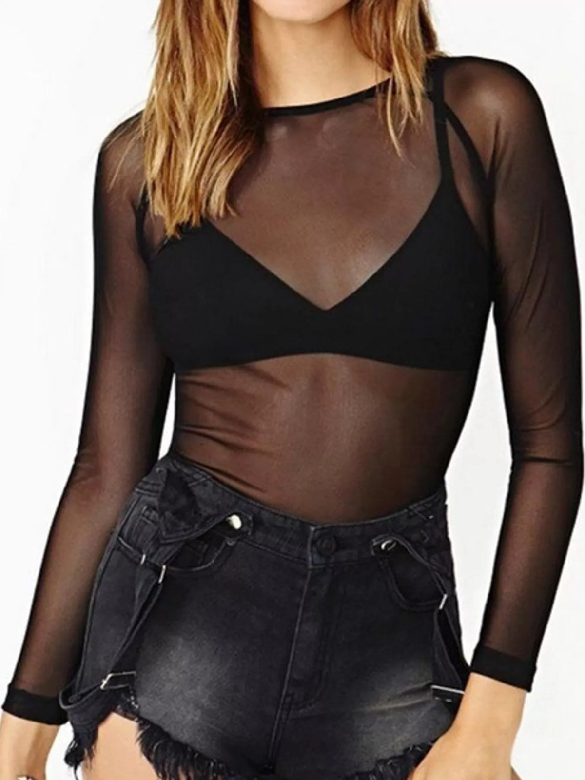 Black mesh long sleeve top worn over triangle bralette tucked into frayed black denim shorts