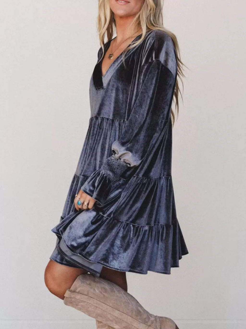 Profilo laterale di un vestito in velluto blu scuro che evidenzia il taglio largo, i volant a livelli e le maniche a palloncino