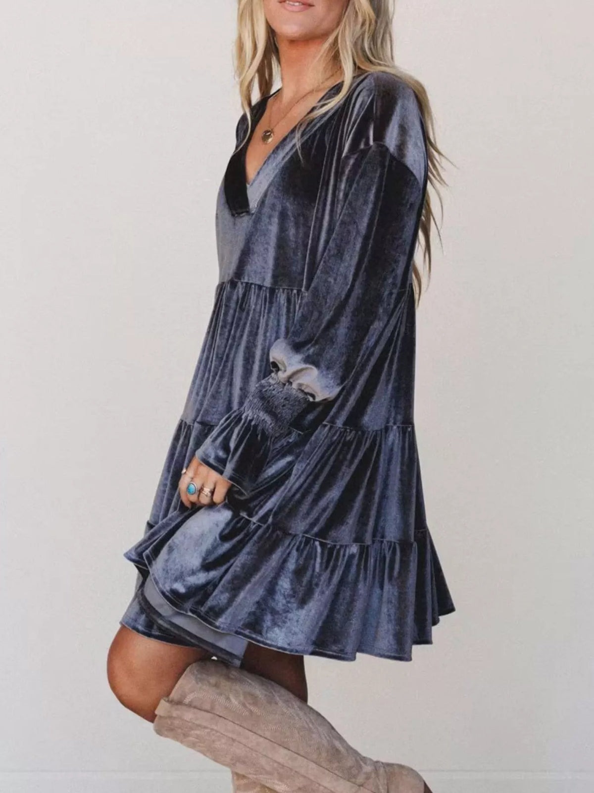 Profilo laterale di un vestito in velluto blu scuro che evidenzia il taglio largo, i volant a livelli e le maniche a palloncino