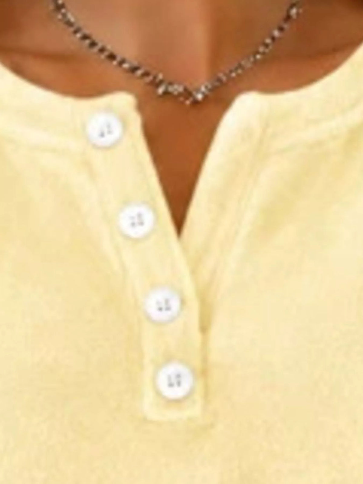 Yellow sweatshirt chest detail showing textured fabric and vertical white button placket