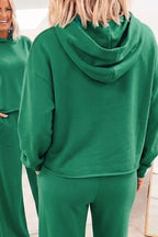 Primer plano del respaldo y capucha de la sudadera verde, mostrando textura de tejido suave y reflejo parcial del espejo.