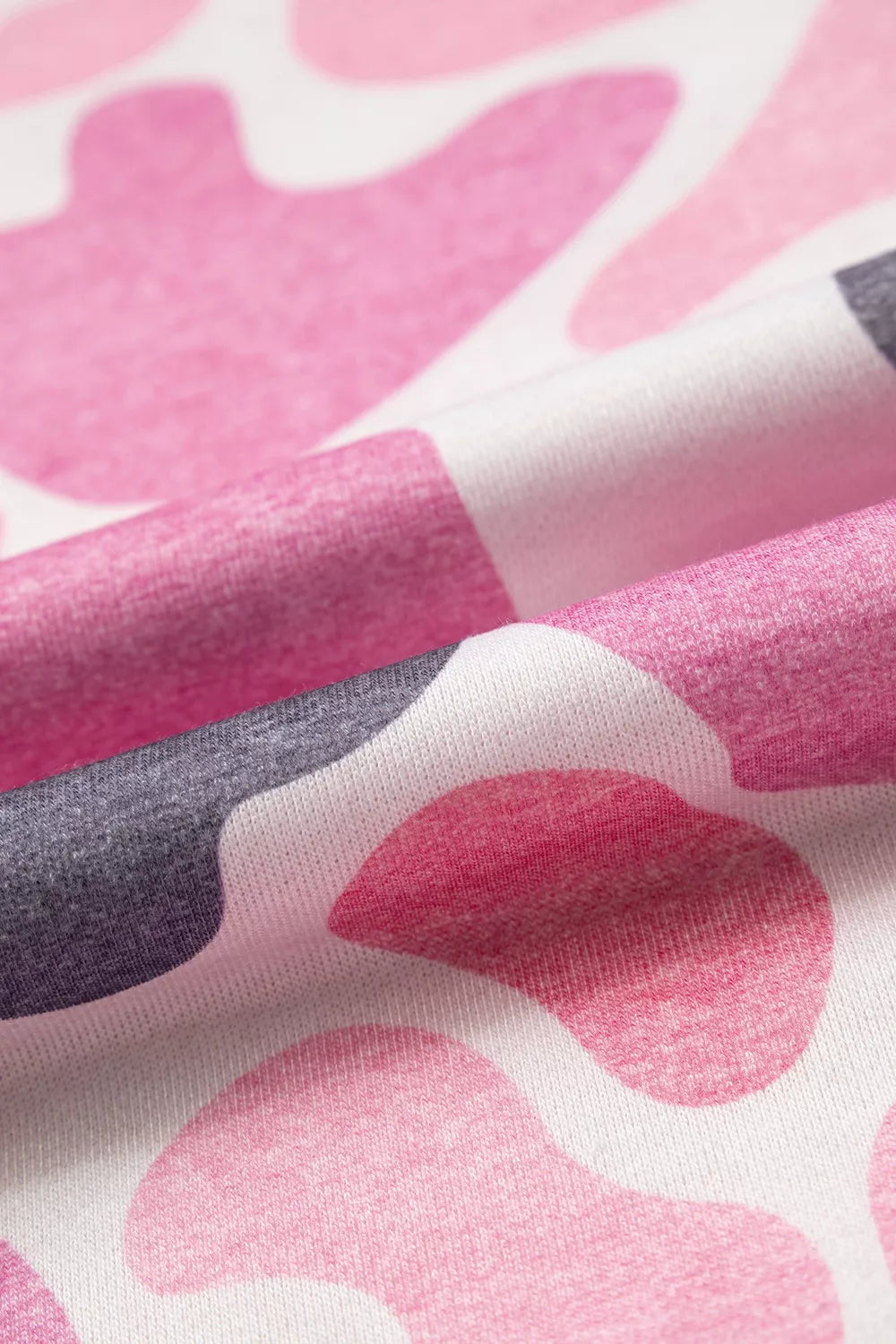 Extreme close-up of heathered pink and grey abstract blob texture on white background fabric