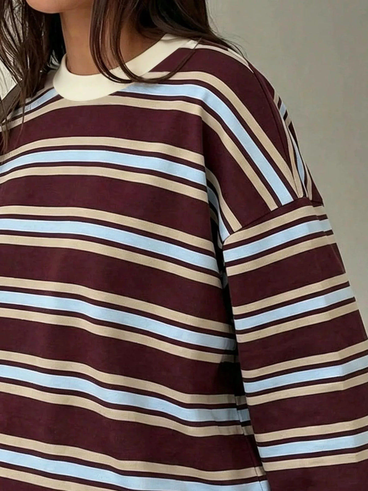 Close-up of maroon striped t-shirt with light blue and beige bands highlighting soft fabric texture and relaxed shoulder seam