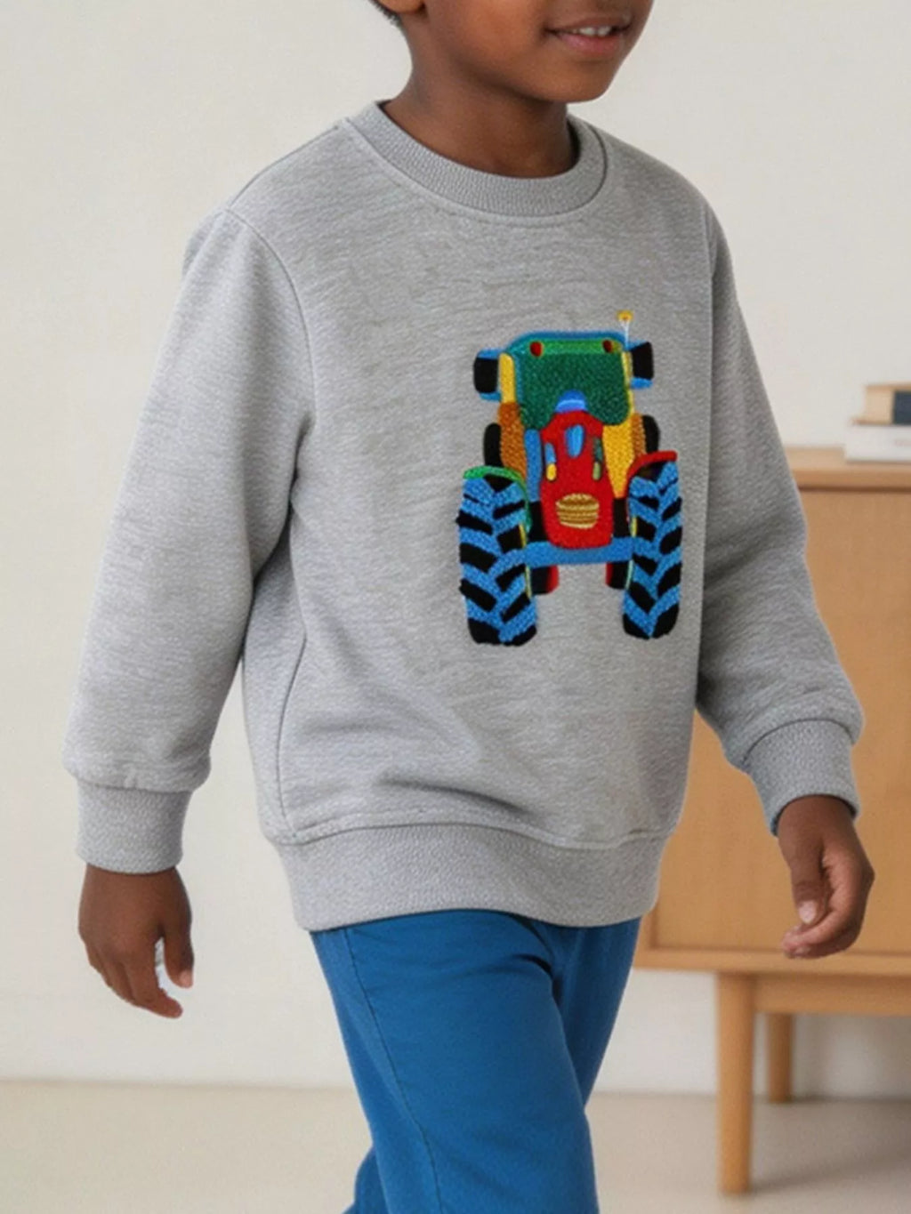 Seitenansicht eines Kindes im grauen Langarm-Sweatshirt mit gerippten Bündchen und lockerer Passform