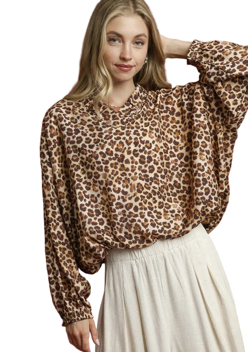 Latte leopard print blouse with ruffled mock neck and balloon sleeves on model against red background