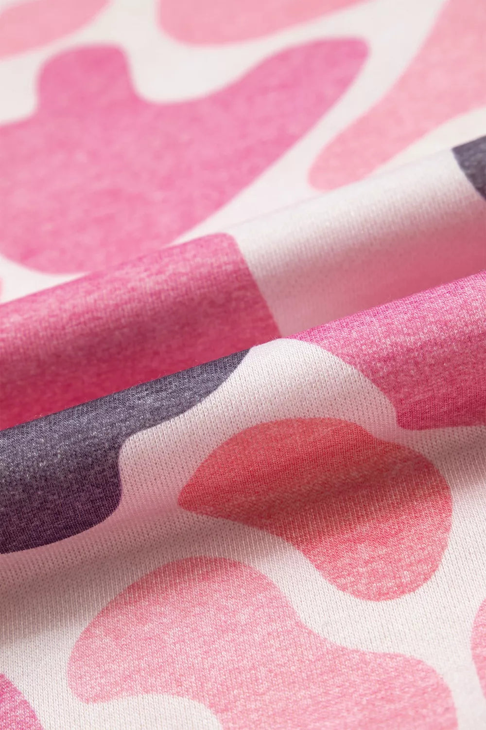 Folded fabric macro emphasizing soft heathered polyester and vibrant pink grey white contrast