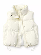 Cream colored puffer vest with vertical pockets and high stand-up collar