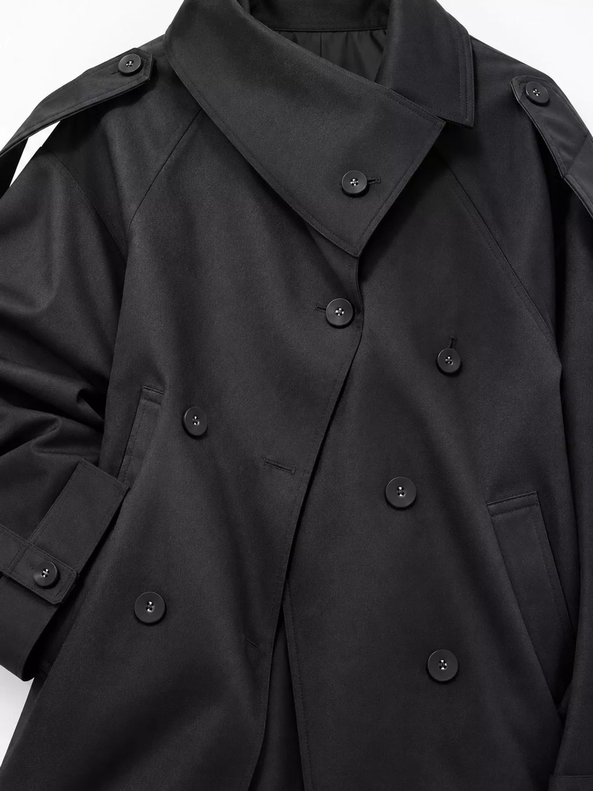 Nahaufnahme des oberen Abschnitts der schwarzen Jacke, glatte Polyester-Textur und Anordnung der vier sichtbaren Knöpfe
