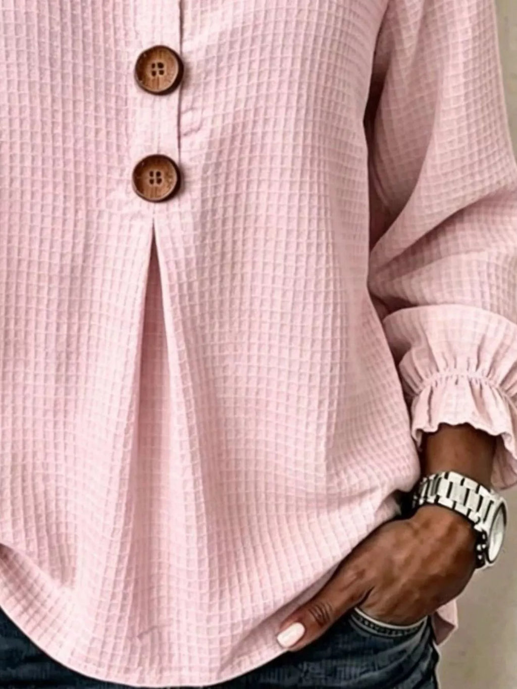 Vista del torso medio de la blusa rosa con abertura de botonadura y reloj plateado