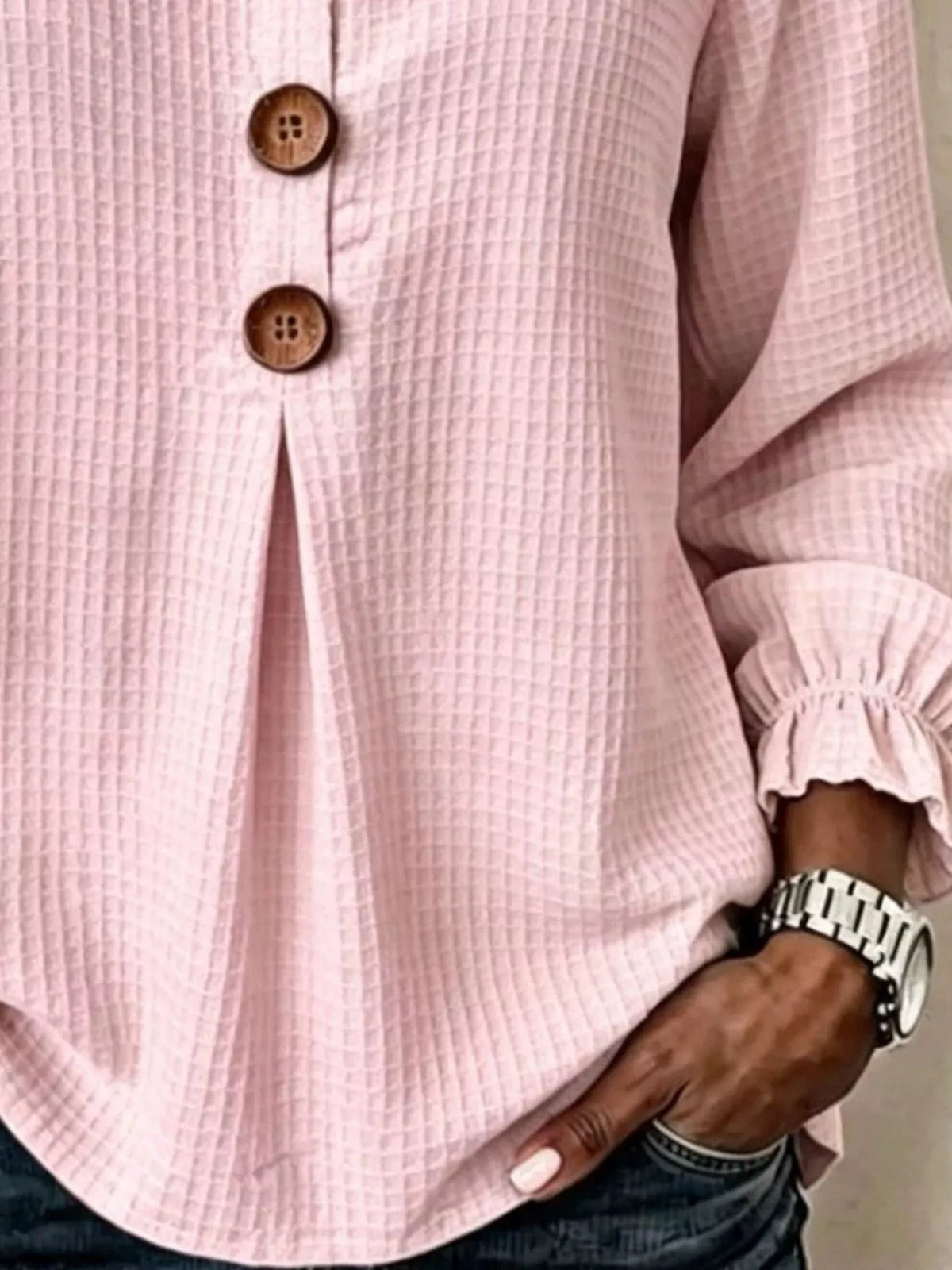 Vista del torso medio de la blusa rosa con abertura de botonadura y reloj plateado