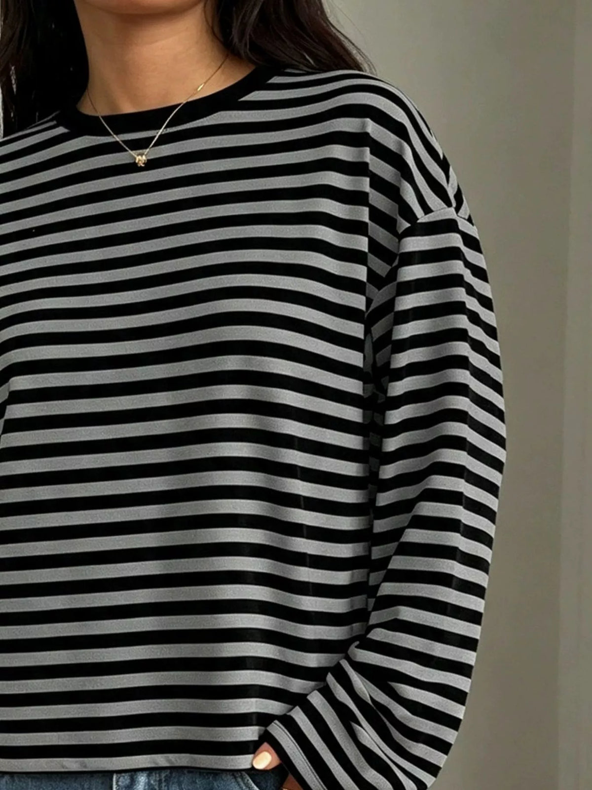 Close-up of black and grey striped fabric texture showing ribbed crew neckline and consistent horizontal stripe pattern