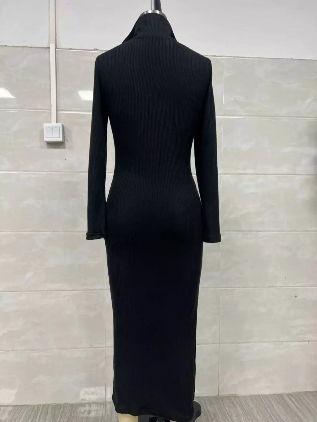 Vue arrière d'une robe pull tricotée côtelée noire sur mannequin mettant en valeur la texture côtelée verticale et la taille/hanches ajustées