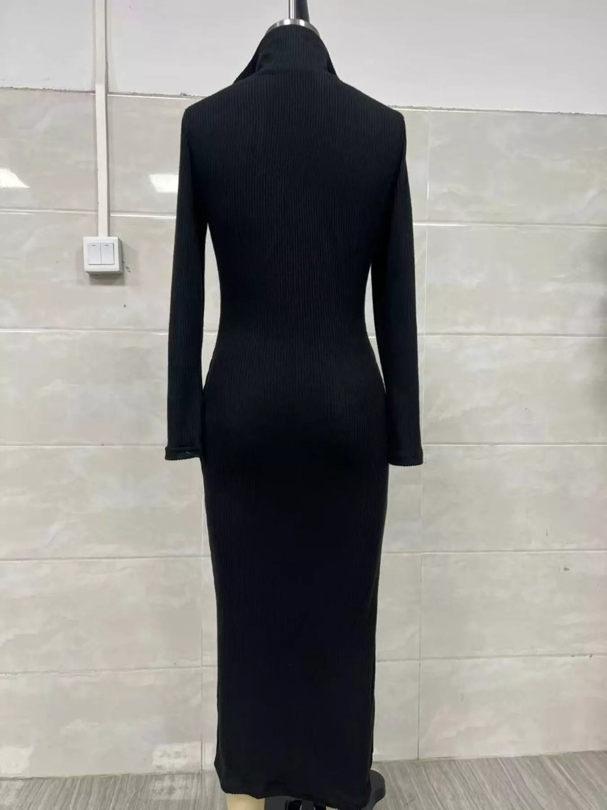 Vue arrière d'une robe pull tricotée côtelée noire sur mannequin mettant en valeur la texture côtelée verticale et la taille/hanches ajustées