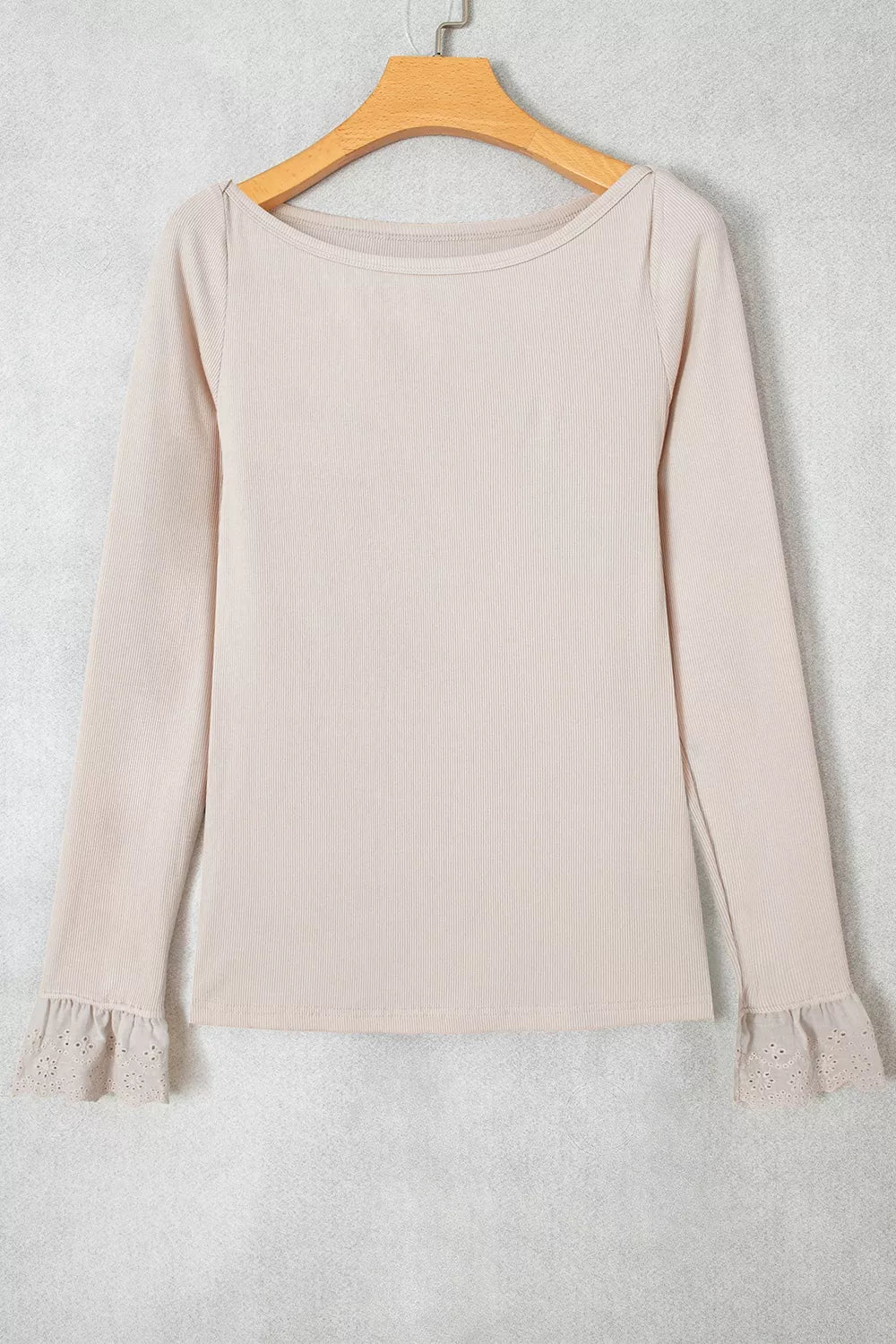 Flat lay of beige ribbed top on hanger displaying boat neck and lace patchwork