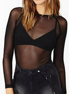 Model in black sheer mesh long sleeve top with high neck over black bralette and denim shorts