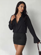 Mannequin robe mini noire à boutons, profond V et volants, tenant sac marron