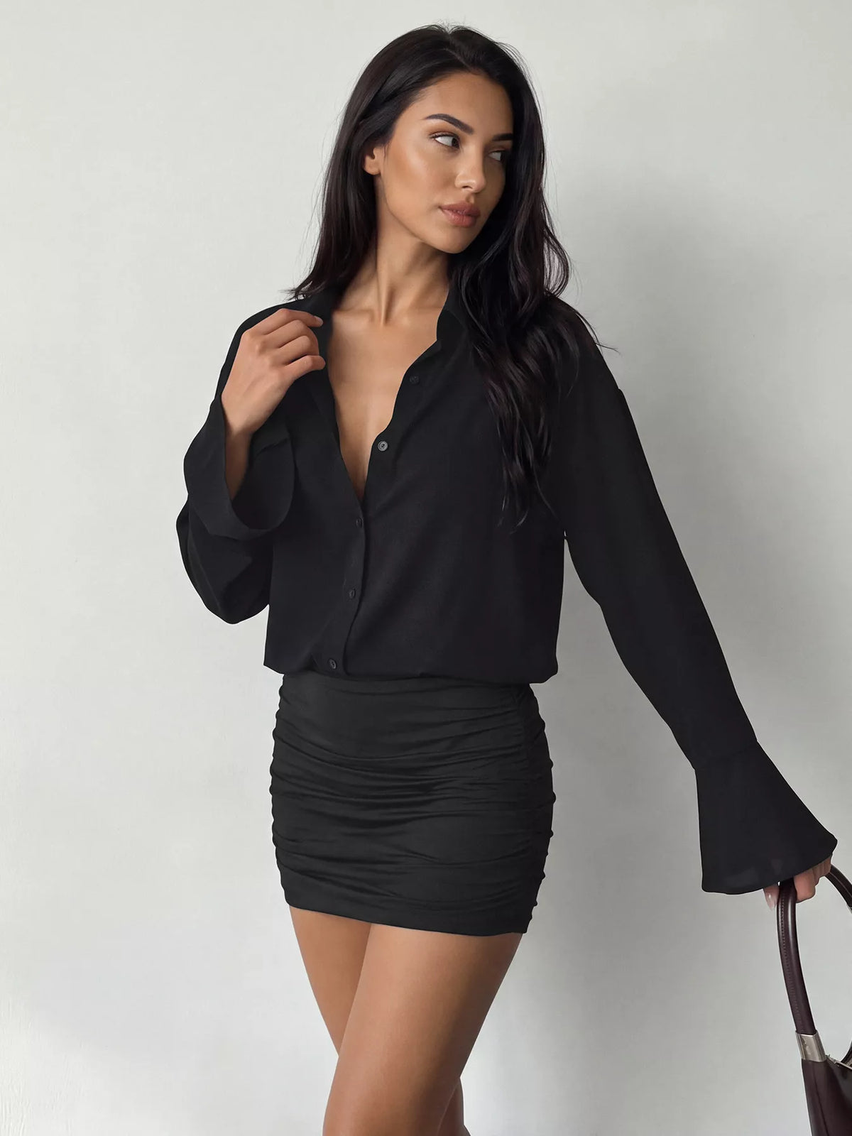 Mannequin robe mini noire à boutons, profond V et volants, tenant sac marron