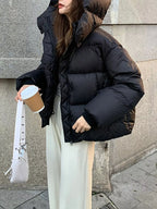 Model against grey wall in black quilted jacket showing diamond-quilted pattern and thick thermal construction