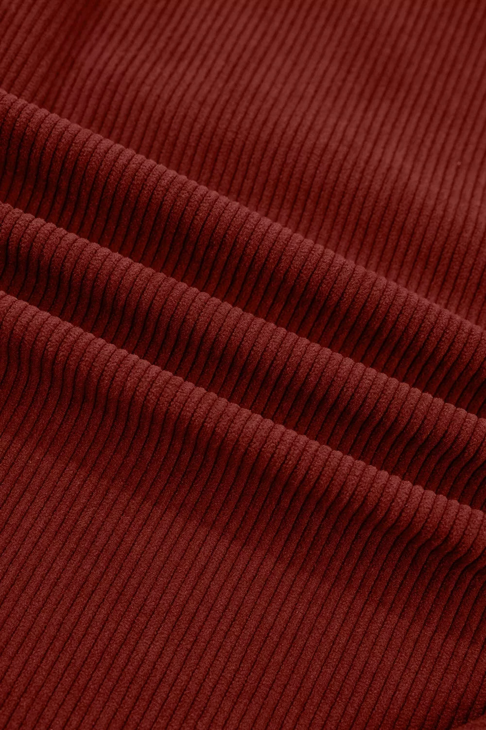 Macro of rich burgundy corduroy material showing vertical wale pattern and drape