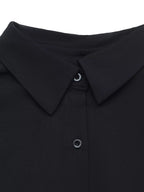 Détail col robe chemise noire : design pointu, boutons ronds foncés et couture précise