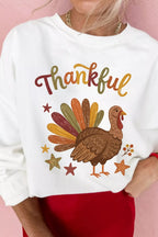 Nahaufnahme des weißen Thanksgiving-Sweatshirts: brauner Truthahn und Goldkette vor rosafarbenem Hintergrund
