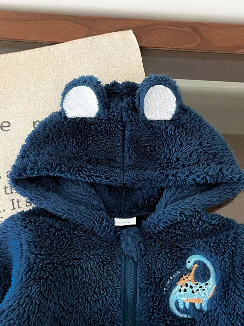 Close-up of navy blue soft plush hoodie showing textured fabric, upright bear ears, and embroidered light blue dinosaur