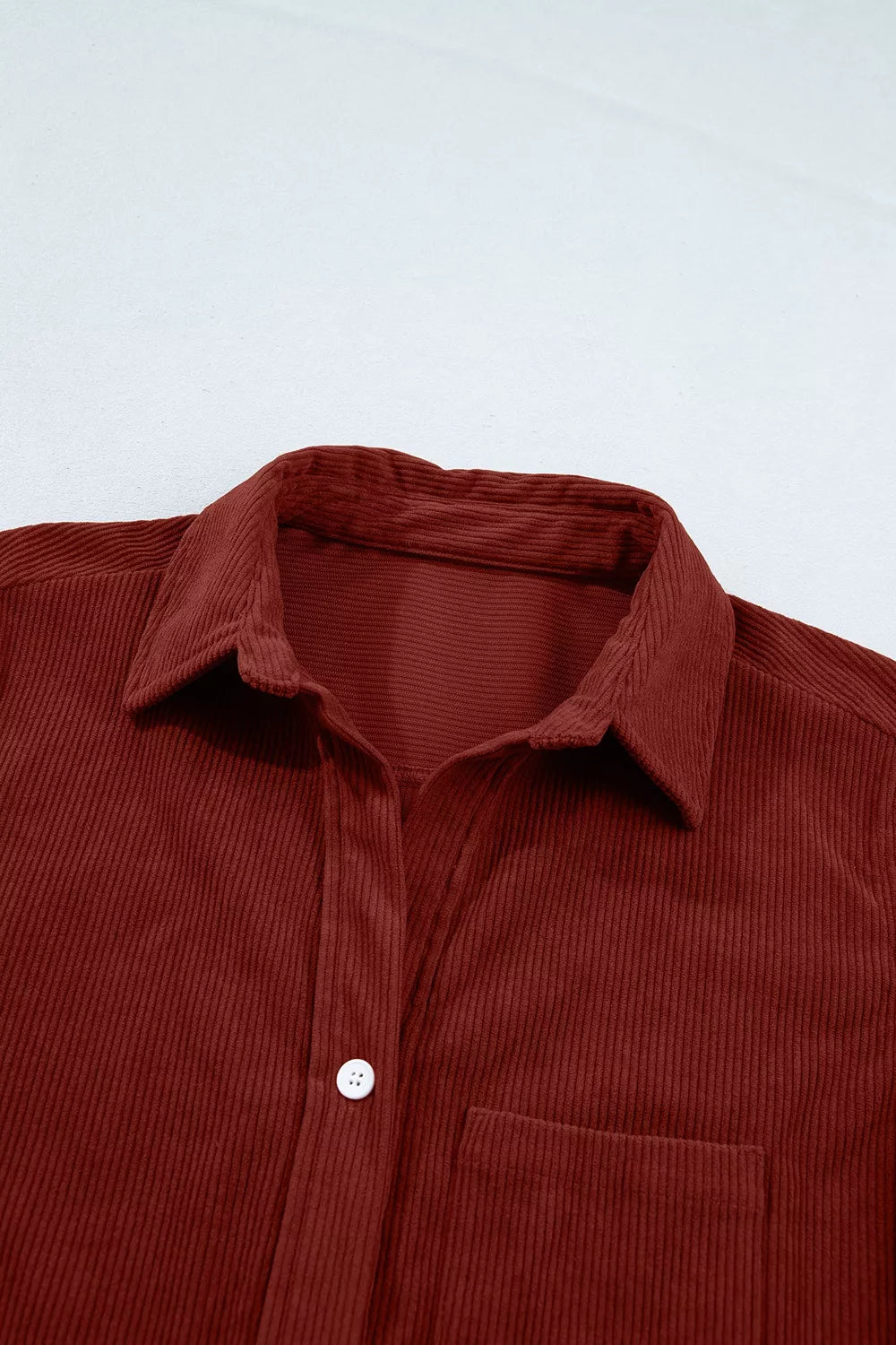 Detail of structured pointed collar and top white button on thick vertical ridges