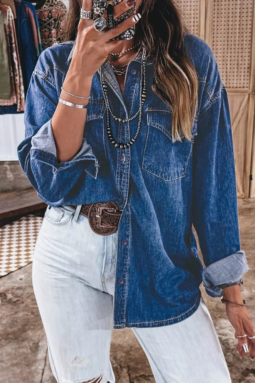 Vista frontal de camisa vaquera manga larga holgada, cierre con botones y bolsillos pecho, con jeans y cinturón.