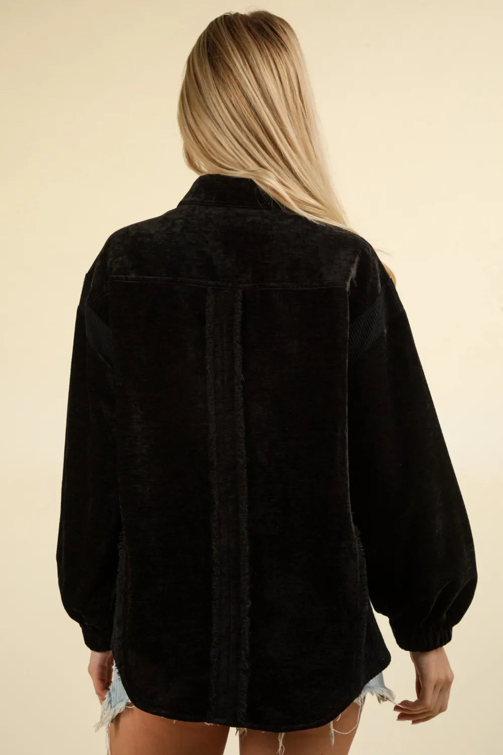 Rear view of oversized black shacket showing drop shoulders, velvet texture, and curved raw hemline