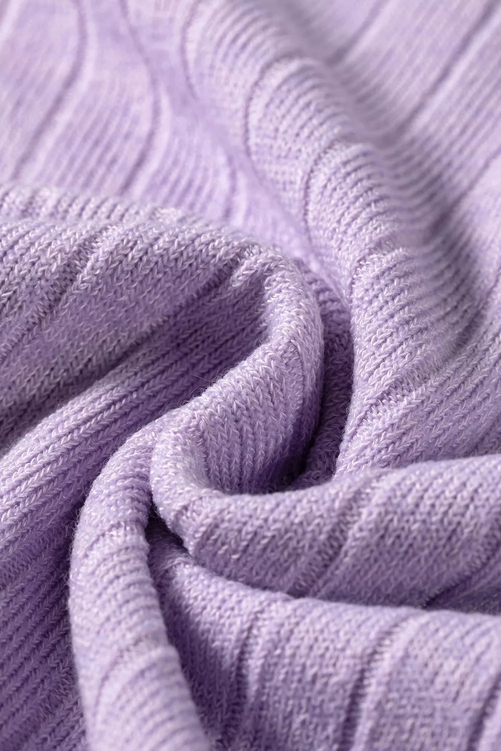 Swirling folds of light purple ribbed sweater fabric showcasing elasticity and plush synthetic blend