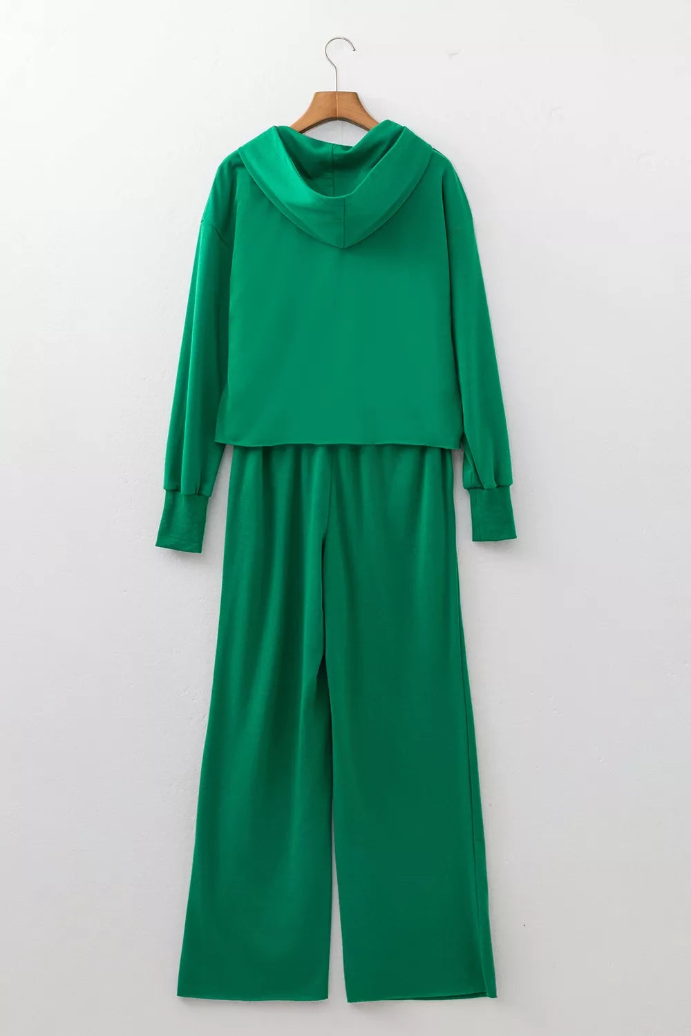 Vista trasera del conjunto verde en percha, destacando panel liso de sudadera y pantalones rectos para uso casual.