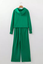 Vista trasera del conjunto verde en percha, destacando panel liso de sudadera y pantalones rectos para uso casual.