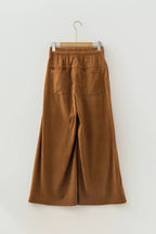 Plano trasero de pantalones de pana camel colgados, destacando la colocación de los bolsillos traseros rectangulares