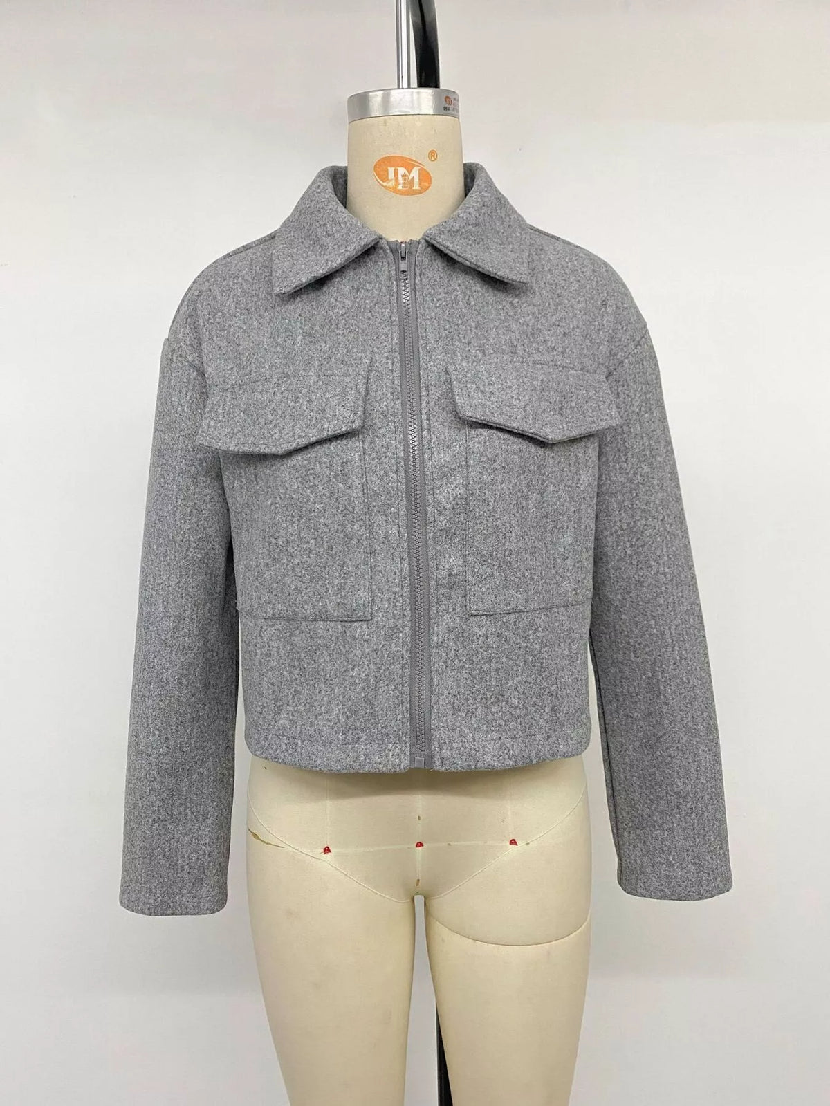 Frontalproduktshot der grauen Perfee Jacke am Mannequin mit geschlossenem Zentralreißverschluss, symmetrischen Klappentaschen und strukturierter Form