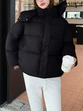 Model in black oversized puffer jacket holding coffee cup, highlighting relaxed fit and side pockets