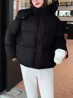 Model in black oversized puffer jacket holding coffee cup, highlighting relaxed fit and side pockets