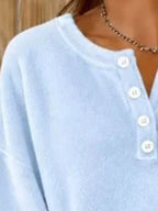Light blue sweatshirt neckline close-up highlighting clean stitching and white button arrangement