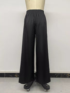 Rear view of black wide-leg pants on mannequin emphasizing loose flowing floor-length cut