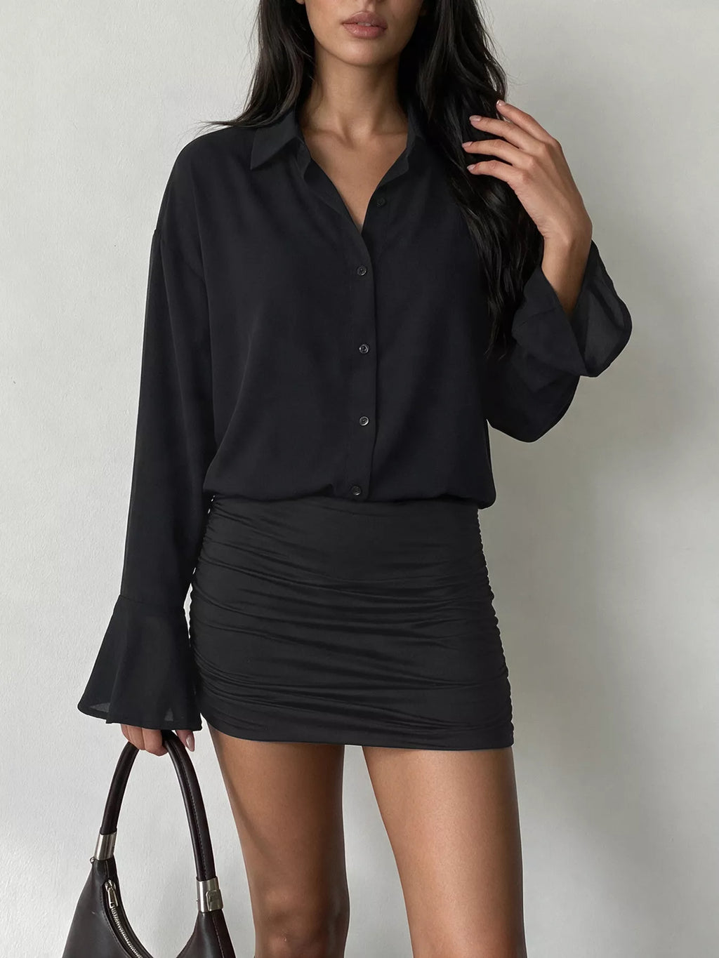 Lifestyle mannequin robe noire tenant sac, V nu, main dans les cheveux