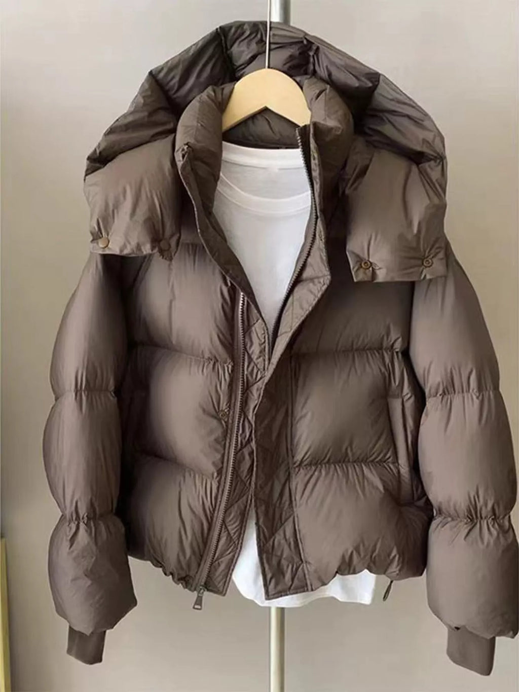 Brown quilted hooded puffer jacket hanging open on hanger displaying diamond-stitched inner placket