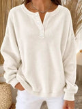 Cream henley sweatshirt with four white buttons and loose long sleeves on model
