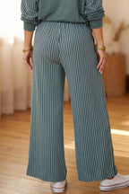 Nahaufnahme der teal Pinstripe-weiten Hose zeigt Stofffall und Hände der Model mit goldenen Armreifen