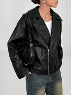 Seitenprofil der voluminösen schwarzen Faux-Leder-Jacke zeigt boxige Silhouette, weite Ärmel, Seitentasche und kleine Schulterdetails.