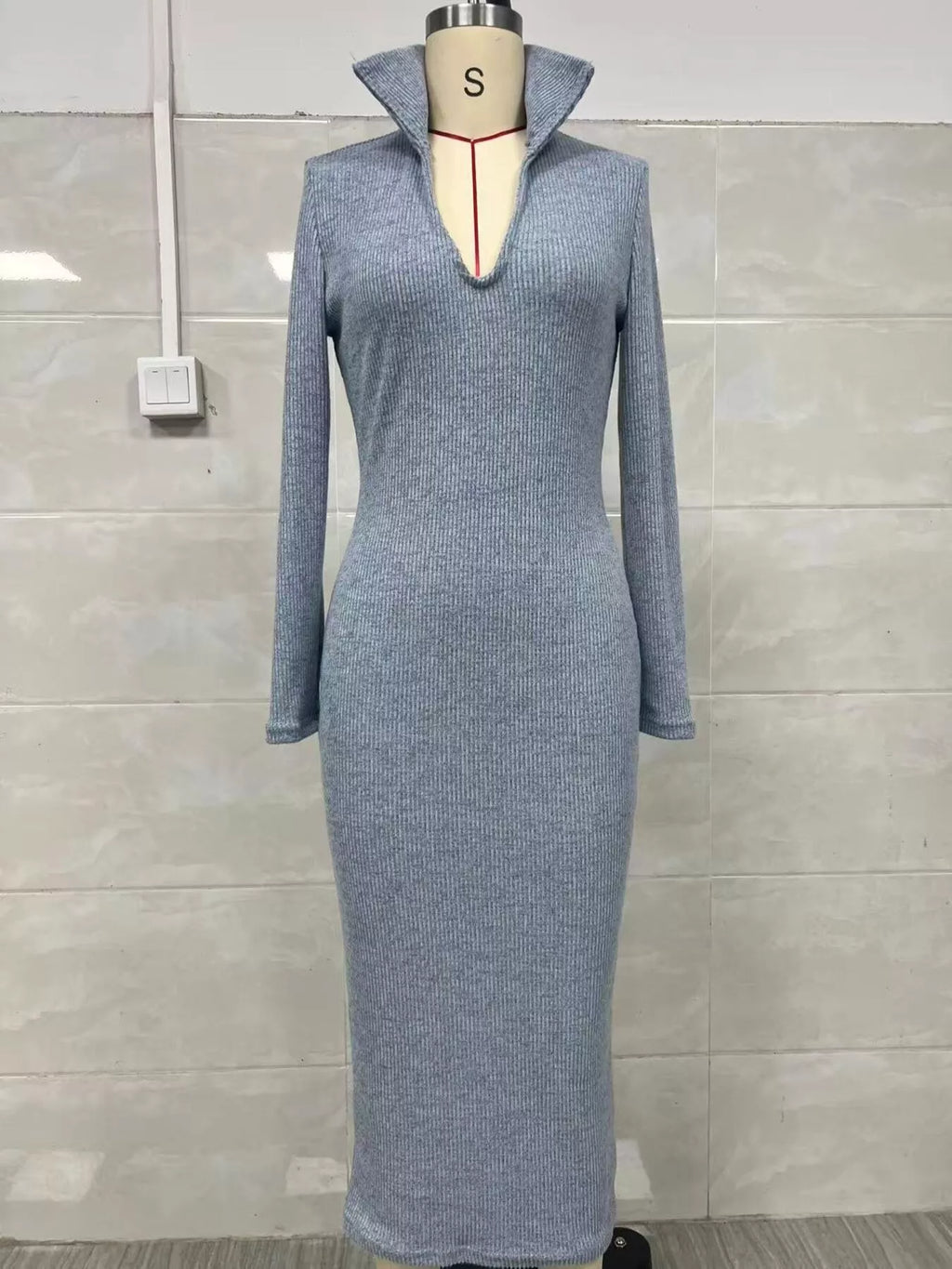 Robe tricotée côtelée bleu-gris clair sur mannequin montrant texture verticale, manches longues et col V ouvert avec haut col roulé
