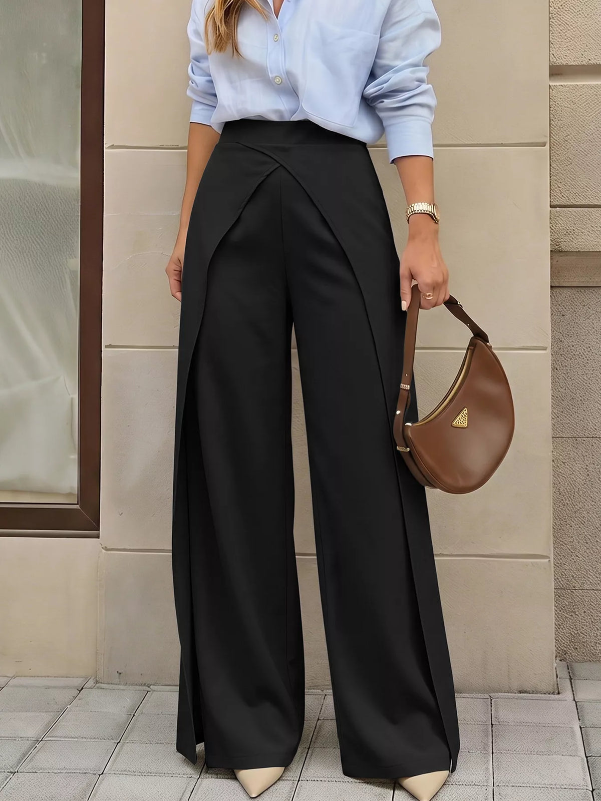 Model wearing black high-rise trousers with asymmetrical waist against beige background