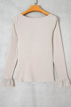 Light beige top hanging on wooden hanger showing ribbed knit and lace details