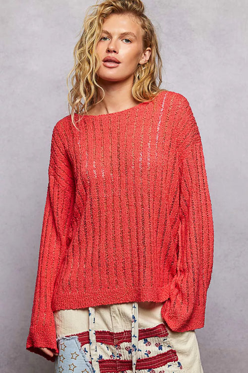 Front view of coral-red long sleeve sweater showing loose draped silhouette and flared bell sleeves