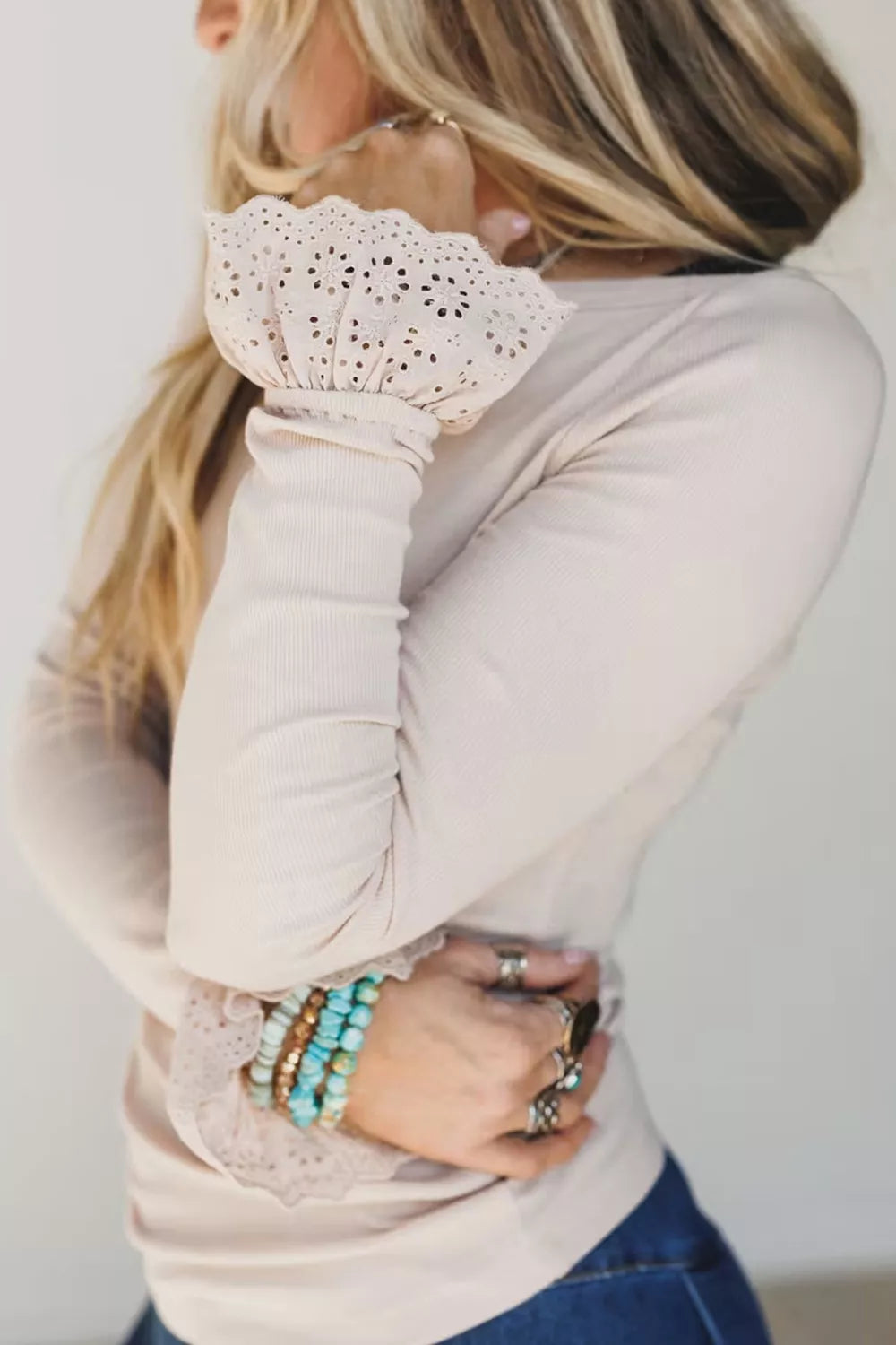 Close-up of floral eyelet lace pattern on scalloped cuff against plain background