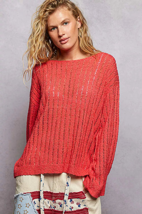 Coral-red open weave sweater with vertical ribbed texture and wide boat neckline against grey background